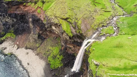 Aerial view of small waterfall ending on North Atlantic sea, Faroe island. Video stock 102135779