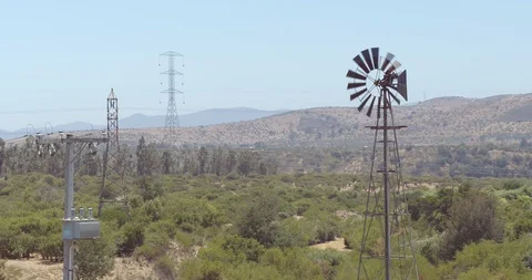 AERIAL VIEW OF A SMALL WINDMILL IN THE VALLEY WITH A LOT OF GREEN MOUNTAINS 4k Video stock 101243611