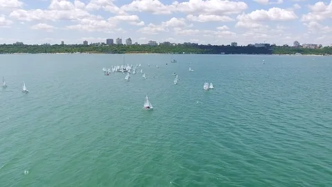Aerial view of small yachts training at sea with city on background Stock Footage 93570285