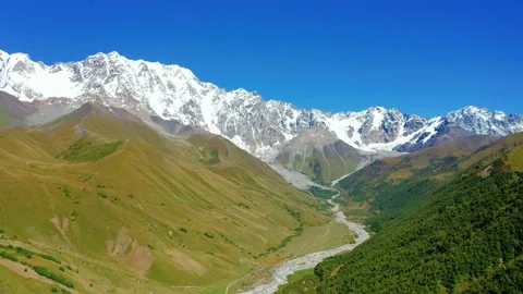 Aerial view of a snow-capped mountain ridge on a summer sunny day against a blue Stock Footage 160794061