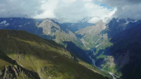 Aerial view of snow-capped mountain peaks covered by clouds and blue sky on a Stock Footage 160846286