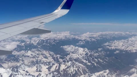 Aerial view of snow capped mountains and blue sky from airplane window. Stock Footage 133364565