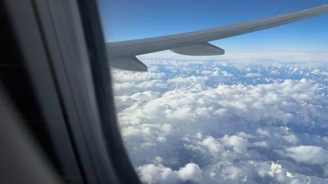 Aerial view of snow-capped mountains and  clouds seen from an airplane window Stock Footage 294103142