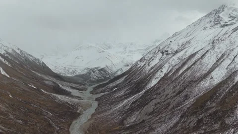 Aerial view of snow-capped mountains and winding river, camera pans across scene Video stock 320396010