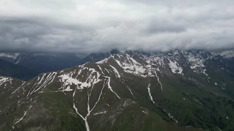 Aerial view of snow-capped mountains under cloudy sky, gradual landscape shift Stock Footage 336963371