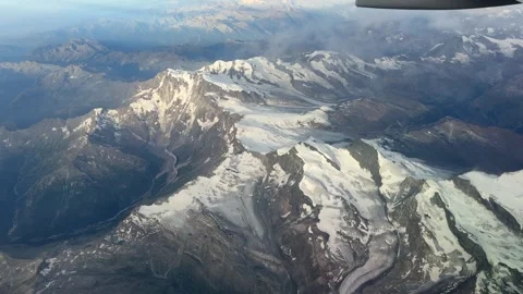 Aerial view of snow-capped mountains and glaciers from an airplane window Stock Footage 339311391