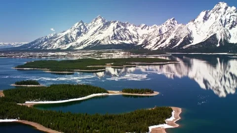 Aerial view of snow-capped mountains reflecting in serene lake with islands. Stock-Footage 341068077