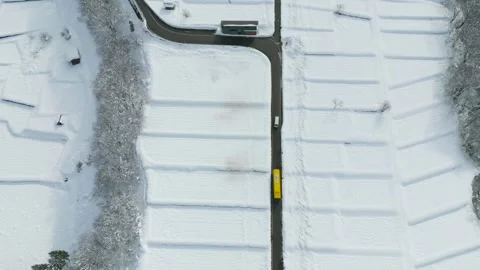 Aerial View of Snow-Covered Fields with a Yellow Bus on a Winter Road Stock Footage 302528029