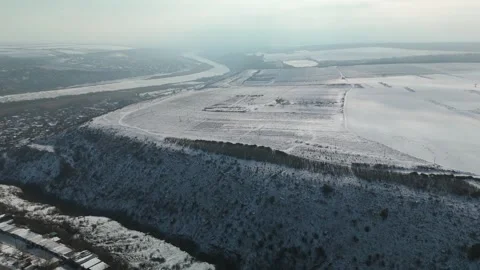 Aerial view of snow-covered hillside with river winding through valley, Stock Footage 332723917