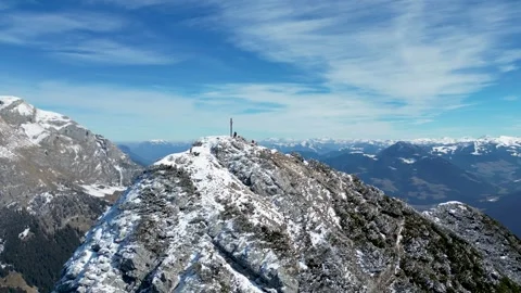 An aerial view of a snow-covered mountain in the Alps, featuring a summit cross Stock Footage 303668145