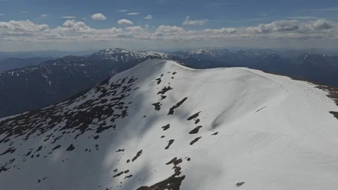 Aerial view of a snow-covered mountain peak with contrasting dark rock patches 動画素材 333828885