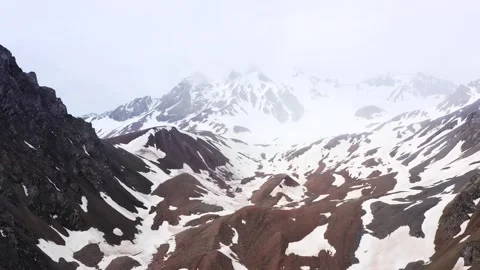 Aerial View of Snow Covered Mountain Peaks and Rocky Slopes in Winter Season Stock Footage 342239332