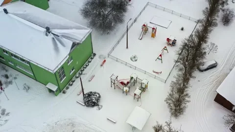 Aerial view of snow falling on an empty school playground during a winter Stock Footage 346594859