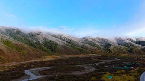Aerial view of snow falling snow covered canyon winding mountain road river Stock Footage 337926978