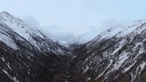 Aerial view of snow mountain valley with winding road Stock Footage 346193373