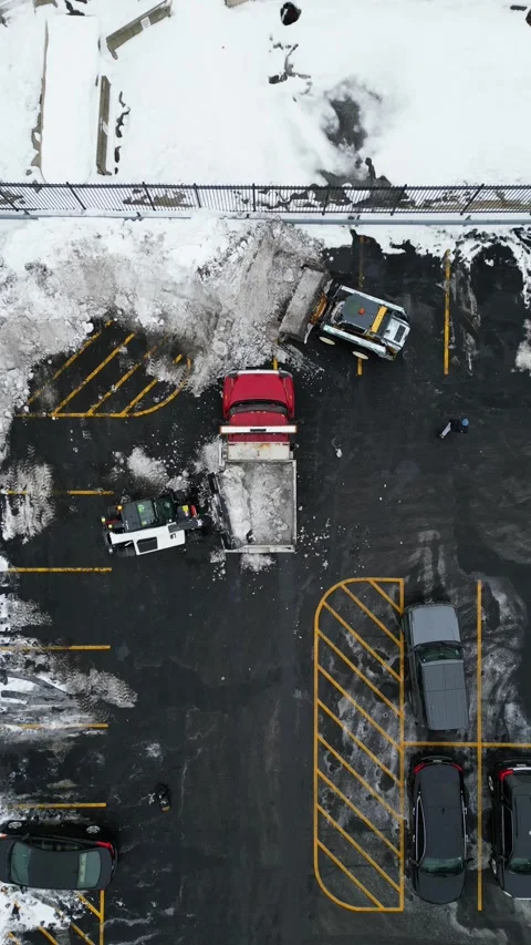 Aerial view of snow removal machinery clearing a parking lot Stock-Footage 332543473