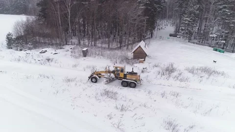 Aerial view of Snowblower Grader Clears Snow Covered Road next to the forest Stock Footage 148251703