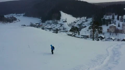 Aerial view of a snowboard going uphill near the village at sunset Stock Footage 150912048