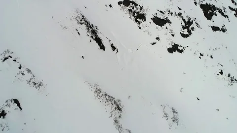Aerial view of snowboarder freeride down from a summit of a winter mountain Stock Footage 78736888