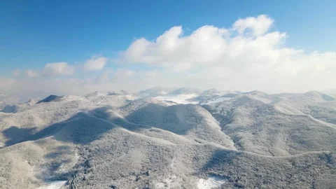 Aerial view of snowcovered mountain range under a clear blue sky Stock Footage 341925457