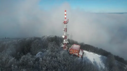 Aerial View of Snowy Communication Tower Amid Winter Forest and Clouds Video stock 340001286