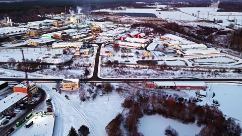 Aerial view of a snowy industrial complex with steam rising from a factory Stock Footage 346596622