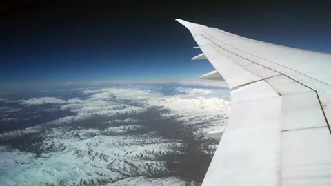 Aerial View of Snowy Mountain Range from Airplane Window Stock Footage 310323548