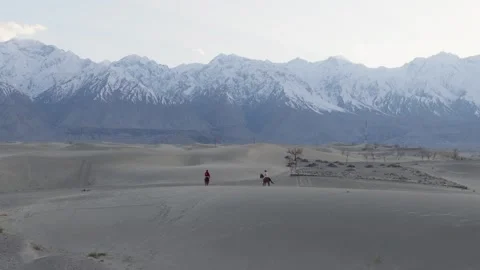 Aerial view of a snowy mountain range in Pakistan, with horseback riders Video stock 314456468