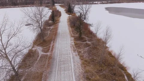 Aerial view of snowy trail between frozen lakes at Golden Ponds Park Video stock 327925933