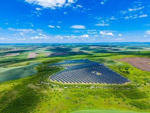 Aerial view solar farm triangular array on rolling green farmland under brigh Stock Photos