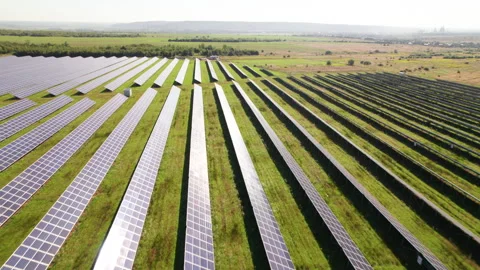 Aerial view of solar modules forming structured rows across green land Stock Footage 346708551