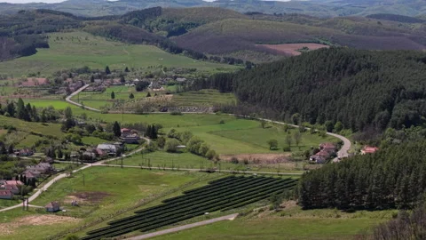 Aerial view of a solar panel array situated in a verdant valley surrounded by Stock Footage 335222428