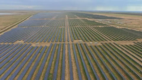 Aerial view of a solar panel farm with sea on the horizon under a cloudy stormy Stock Footage 171027394