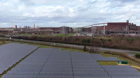 Aerial view of a solar panel farm installed adjacent to a major road with busy Stock Footage 340269047
