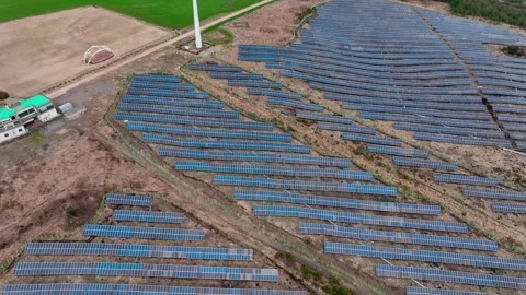 Aerial view of solar panels and wind turbines in Jeju Island Stock Footage 296438399