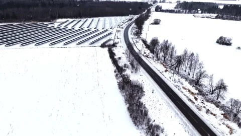 Aerial view of solar panels and a road covered in snow during a winter storm Stock Footage 346594211