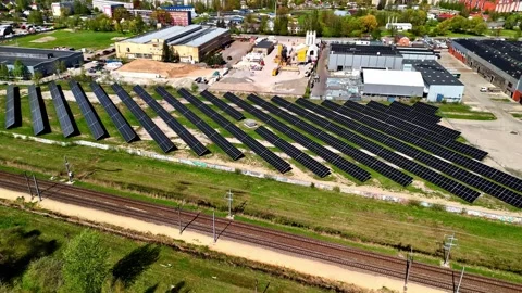 An aerial view of solar panels powering an industrial facility near train tracks Stock Footage 333327062