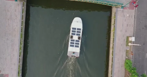 An aerial view of A Solar powered shuttle boat surfing on the canal at centra Stock Footage 274823268