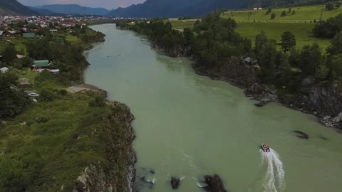 Aerial view of a speedboat navigating a winding green river in a mountain valley 動画素材 345722682