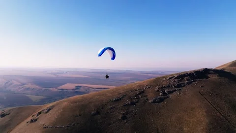 Aerial view, stabilized footage along the horizon. A male paraglider flies Video stock 262455992