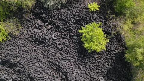 Aerial view of the stark contrast between a massive landfill of used car tires Stock Footage 241010018