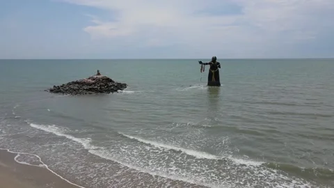 Aerial view of a statue emerging out of the sea on a sunny day. Video stock 204121114