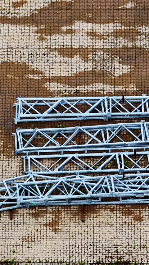 Aerial view of steel truss sections laid out on paved outdoor storage yard 库存影片 337748258