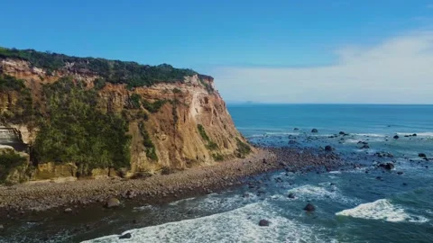 Aerial view of steep cliff meets ocean waves on bright sunny day Stock Footage 344439936