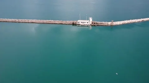 Aerial view of stone breakwater with lighthouse and chapel at sea Stock Footage 337463139