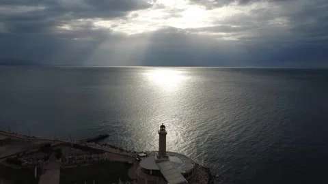 Aerial view of a stone lighthouse on a pier under a dramatic cloudy sky Stock Footage 338106701