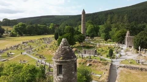 Aerial view of a stone round tower, church and hillside cemetery Stock Footage 348223559