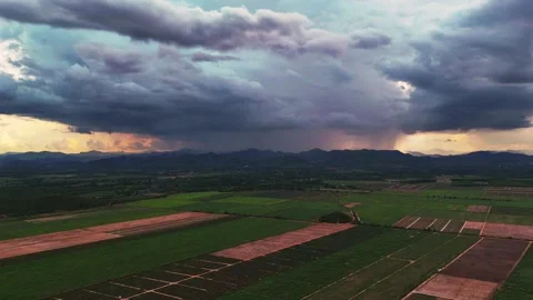 Aerial view of Storm clouds and sunset light over farmland and mountains in Video stock 314414859