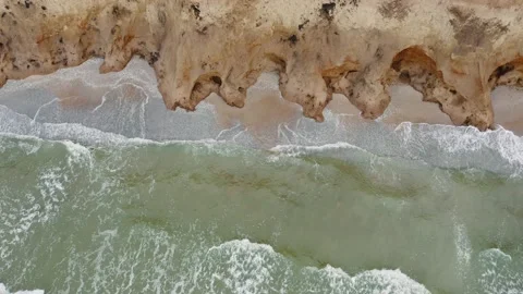 Aerial view of stormy waves beating against a rocky shore on a sandy tropical Stock Footage 156126375