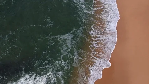 Aerial view straight down at waves crashing on empty sandy beach in summer Stock Footage 95174211